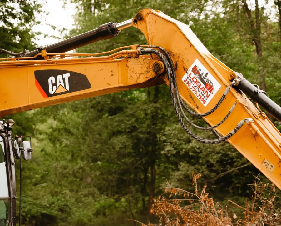 Close view of a CAT excavator boom with a Logan Earthworks decal
