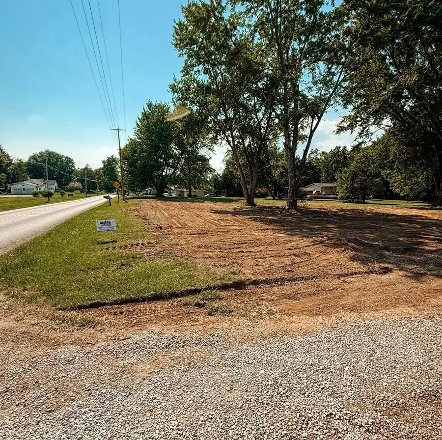 Cleared and graded roadside lot with a small yard sign, gravel in front