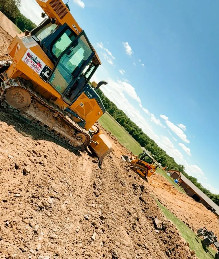 Dozer and compact track loader spreading fill dirt along a slope