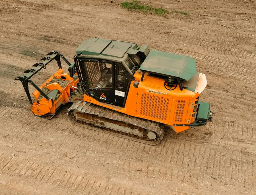 Drone view of a tracked forestry mulcher parked on freshly graded dirt