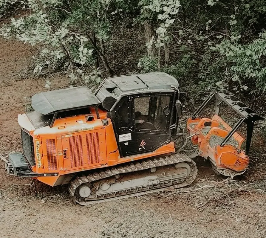 Tracked forestry mulcher working along a treeline, seen from above