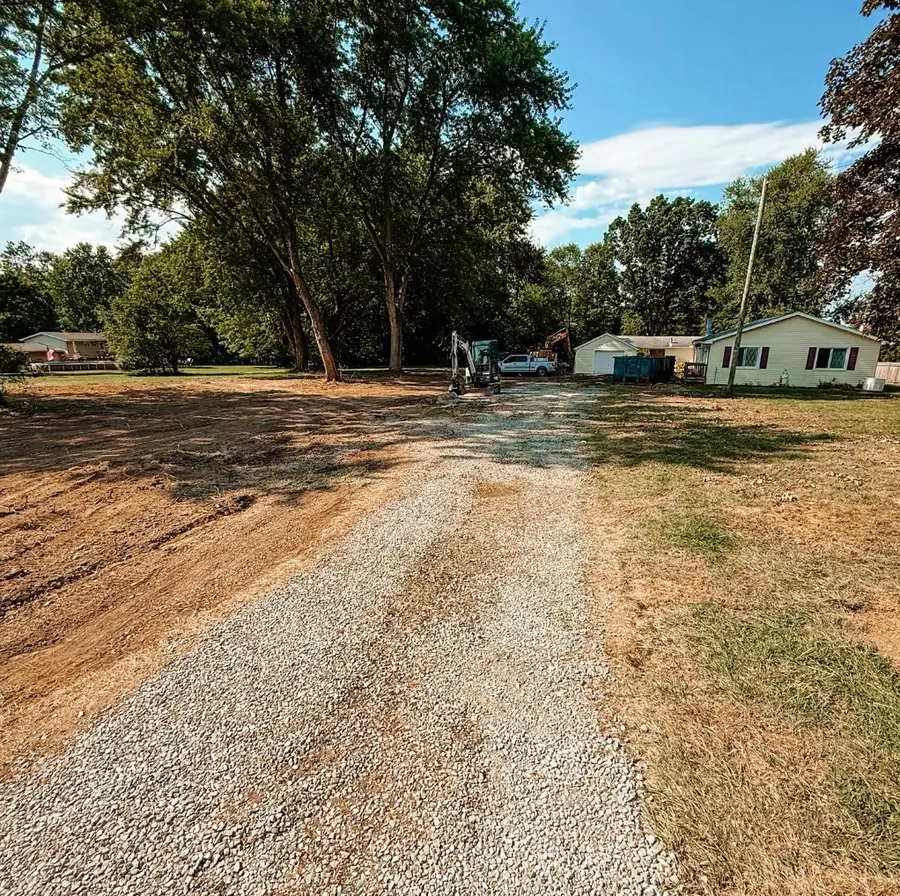 Fresh gravel driveway running to a house with graded dirt alongside